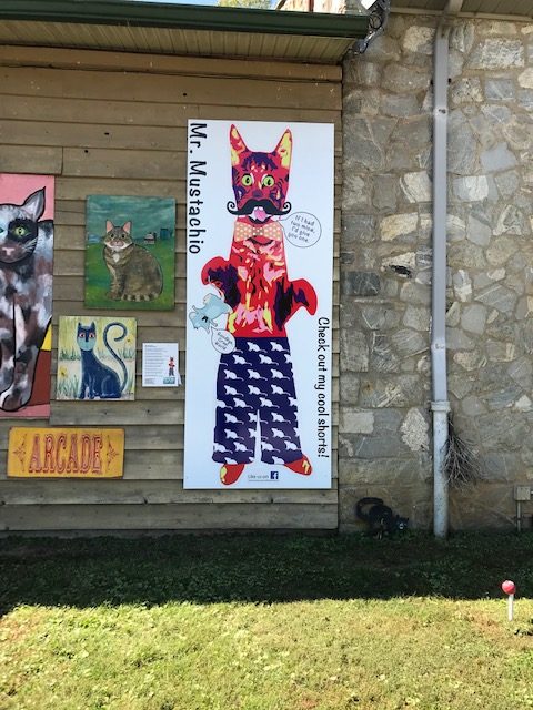 Large folk art painting of a black cat o the side of the museum..