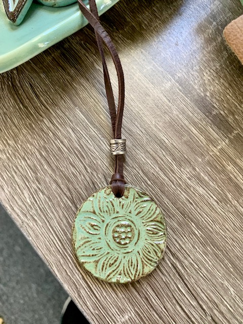 Pottery piece necklace with a sunflower design. 