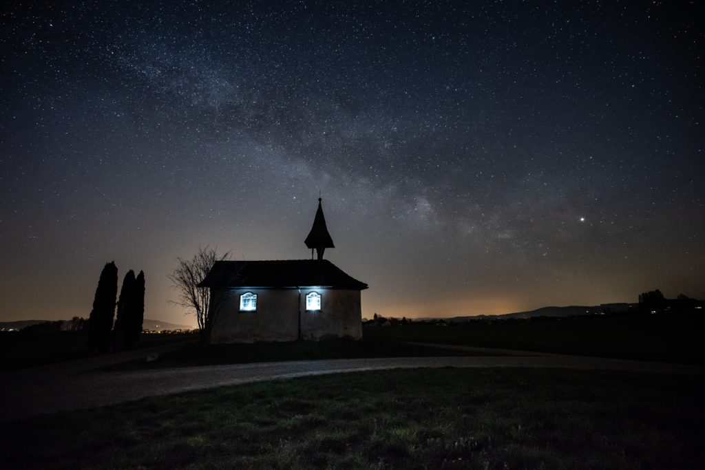 Church lit from within against a starry night background. 