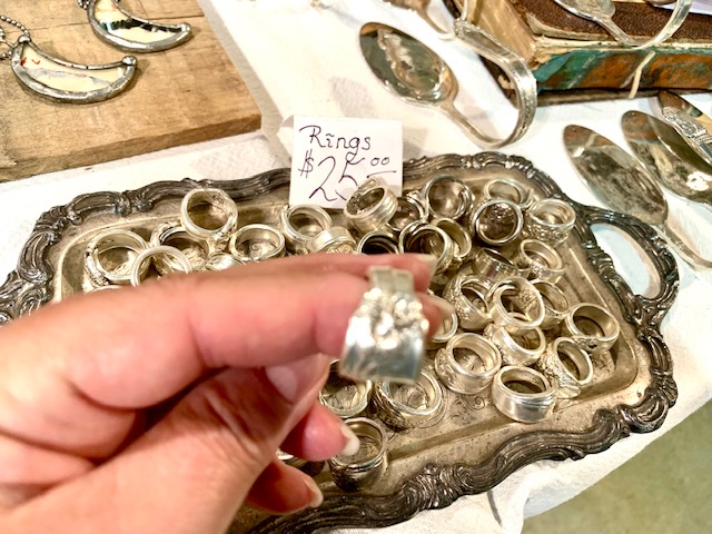 Person holding one of many rings for sale in a tray. 