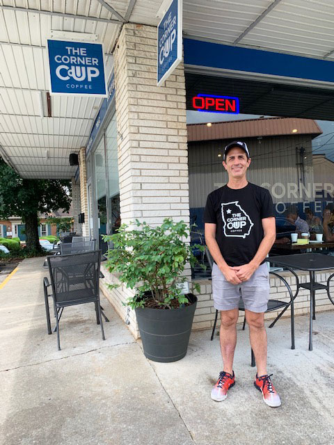 Coffee shop owner posing in front of the store. 
