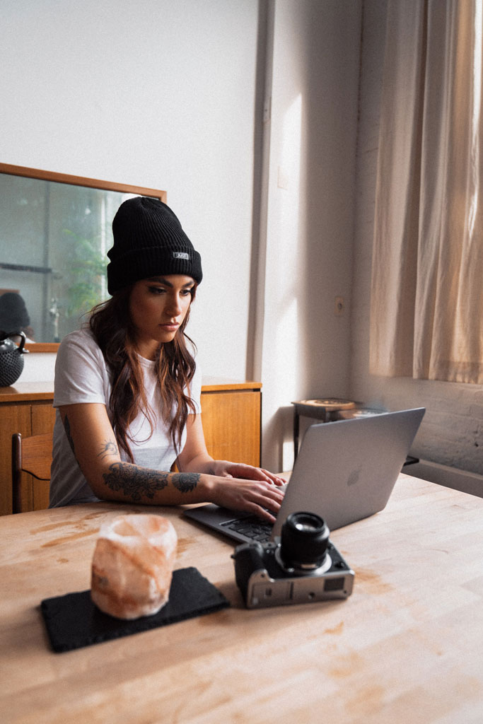 A photographer uploading images from here camera to her laptop.