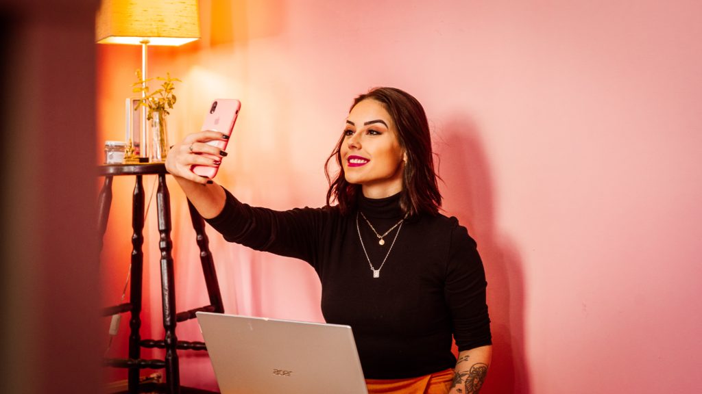 A social media influencer posing in front of her iphone. 