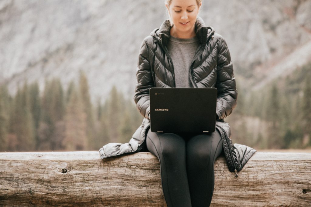 A tourist on vacation working on her laptop in the outdoors. 